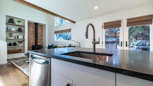 A modern kitchen with a large island, stainless steel appliances, and a brick wall. - Sweet 1Bed/Loft/1Bath EagleVail (Avon)
