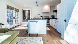 A modern kitchen with a central island, white cabinetry, and a large window with blinds. - Sweet 1Bed/Loft/1Bath EagleVail (Avon)