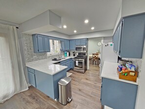 A modern kitchen with blue cabinets, a stainless steel sink, and a built-in oven. - Modern Oasis Near Six Flags & Naval Base! (Gurnee)