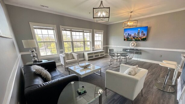 A modern living room with a glass coffee table, leather sofa, and a dining area with a glass table and chairs. - Relaxing Now and Zen: Modern Condo, Near UNCC, PNC Pavilion, Pool, 5 Min to Dining, Shops, +15% off! (Charlotte)