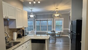 A kitchen with white cabinets, a dishwasher, a black refrigerator, and pendant lighting. - Relaxing Now and Zen: Modern Condo, Near UNCC, PNC Pavilion, Pool, 5 Min to Dining, Shops, +15% off! (Charlotte)