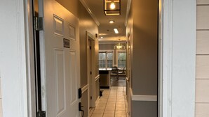 A hallway with a door labeled "9055," a tiled floor, and a hanging light fixture. - Relaxing Now and Zen: Modern Condo, Near UNCC, PNC Pavilion, Pool, 5 Min to Dining, Shops, +15% off! (Charlotte)