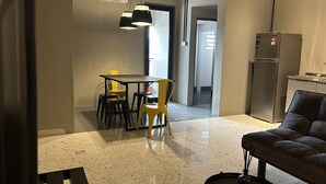 Una cocina moderna con refrigerador, un comedor con mesa y sillas, y una zona de estar con sofá.