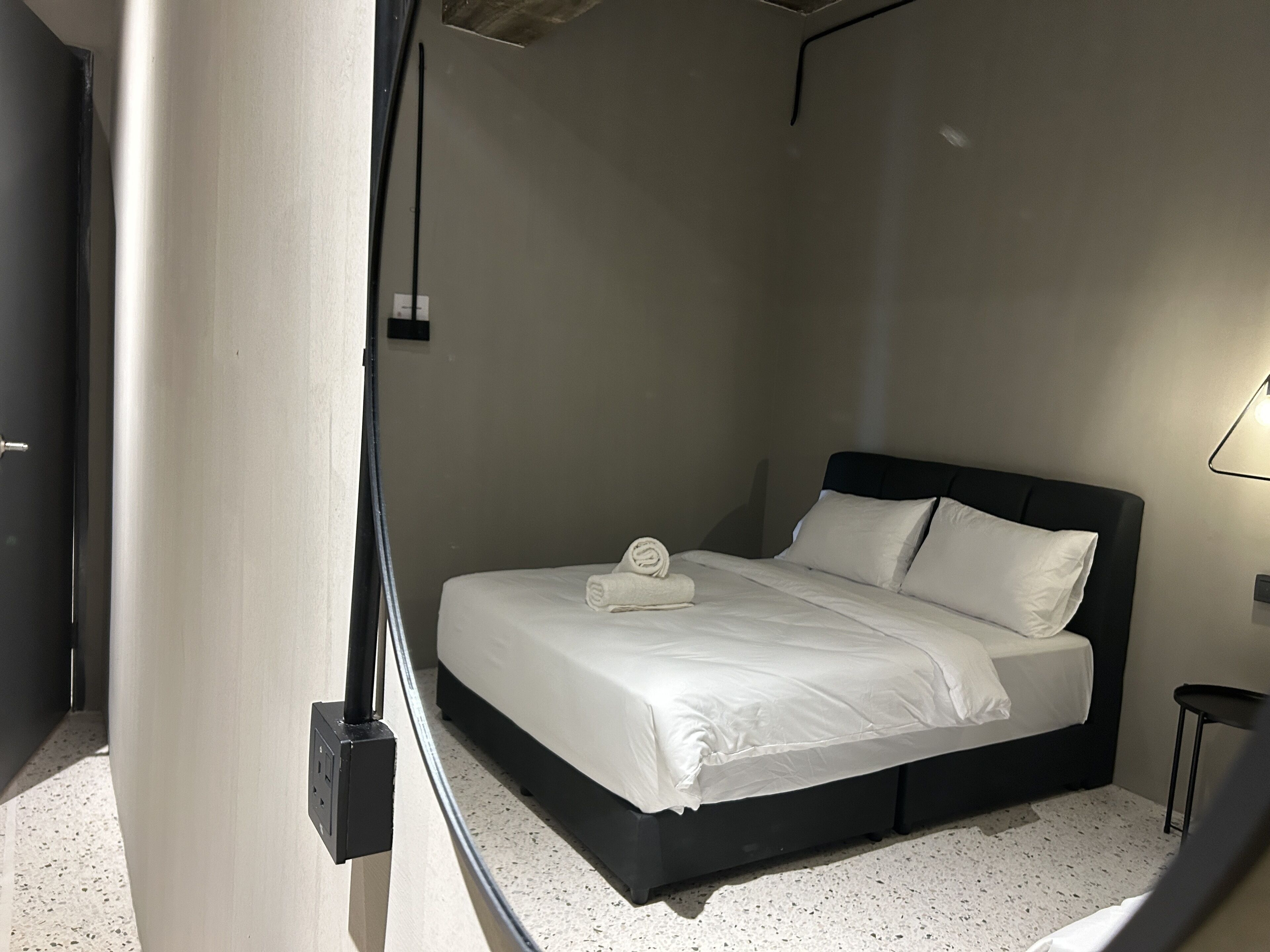 Un dormitorio con una cama, una mesita de noche y una lámpara fijada a la pared.