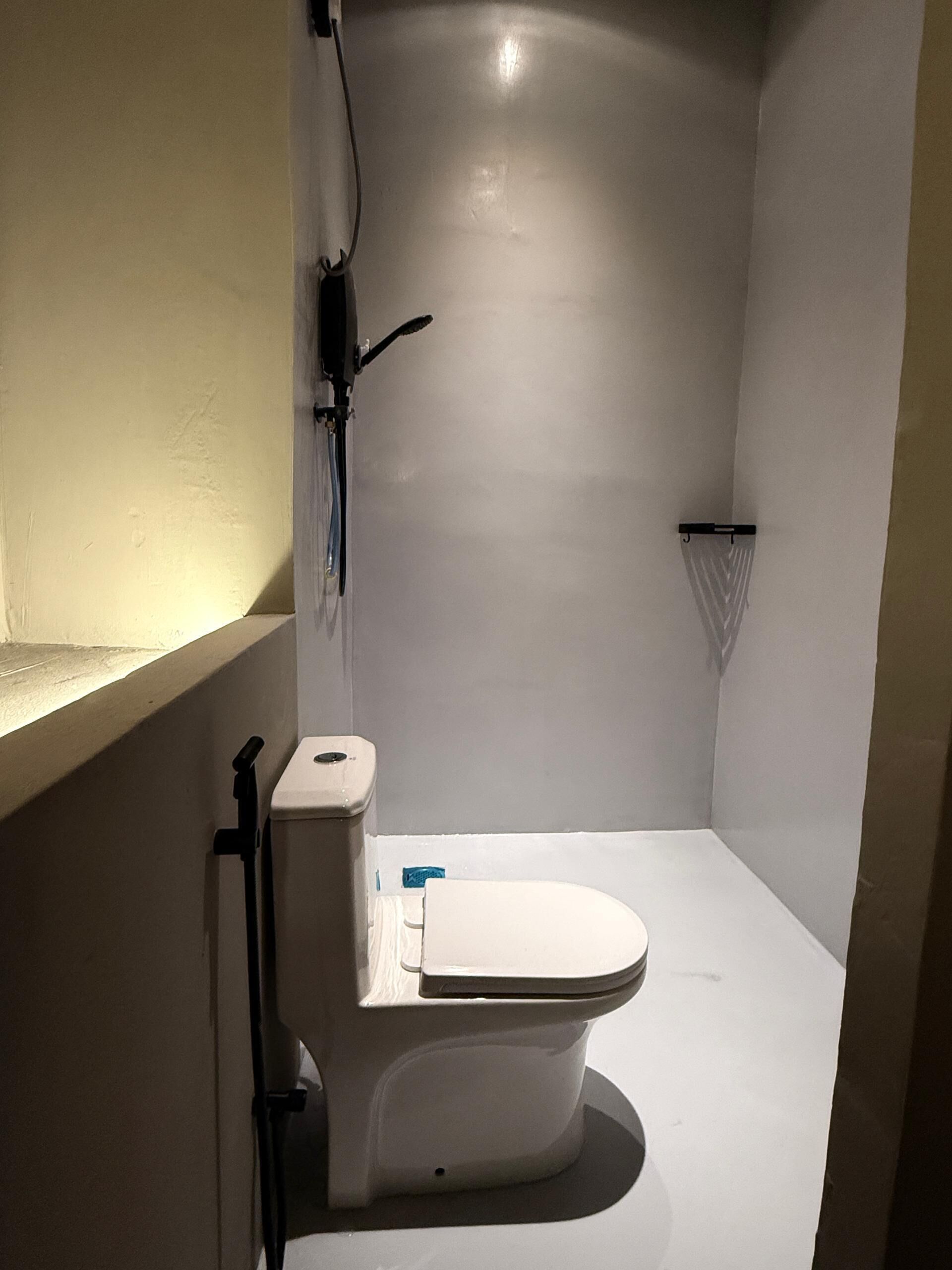 Un baño pequeño y moderno con inodoro, ducha y lavamanos.