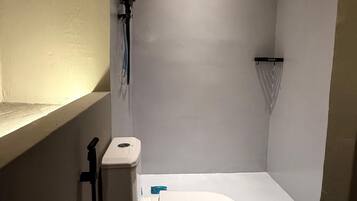 Un baño pequeño y moderno con inodoro, ducha y lavamanos.