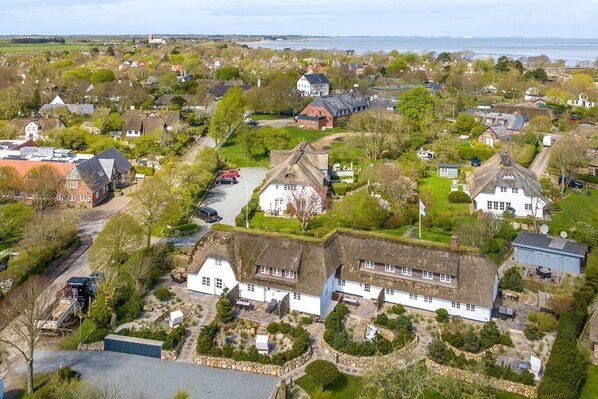 A residential area with houses, a road, and a body of water in the background.