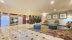 A lobby with a tiled floor, a stone wall with plants, wicker chairs, and framed artwork on the wall. - 2 Queen Beds & a Pool in Waikiki +FREE Parking! (Honolulu)