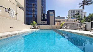 A swimming pool with lounge chairs and a view of tall buildings in the background. - 2 Queen Beds & a Pool in Waikiki +FREE Parking! (Honolulu)
