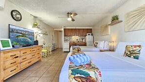 A hotel room with a bed, a desk with a computer, a chair, a small kitchen area, and a clock on the wall. - 2 Queen Beds & a Pool in Waikiki +FREE Parking! (Honolulu)