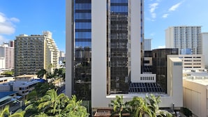 A modern high-rise building with a glass facade, surrounded by other high-rise buildings and palm trees. - 2 Queen Beds & a Pool in Waikiki +FREE Parking! (Honolulu)