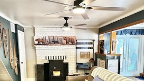 Una sala de estar acogedora con chimenea, un sofá, una mesita de centro y un ventilador de techo.