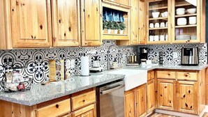 Una cocina con armarios de madera, lavavajillas de acero inoxidable y un salpicadero con diseño.