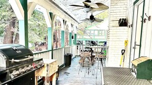 Un patio techado al aire libre con una parrilla, zona de estar y ventiladores de techo.