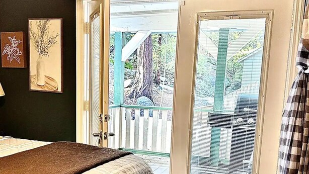 Un dormitorio con cama, ventana que ofrece vistas al exterior y puerta que da al exterior.