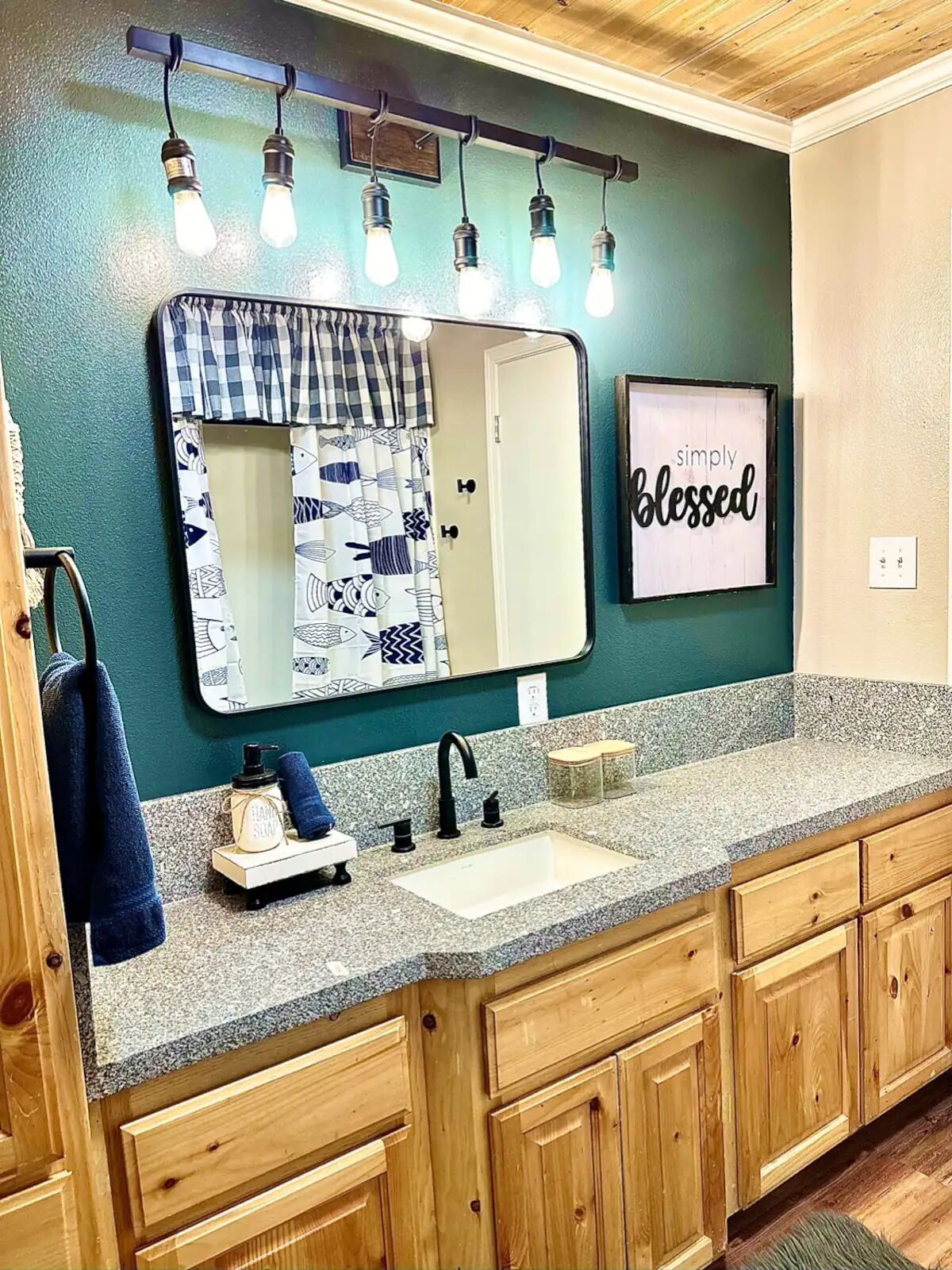 A bathroom with a large mirror, a sink, wooden cabinets, and a towel rack.