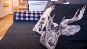 A modern living room with a sofa, a patterned throw pillow, and a kitchen in the background.