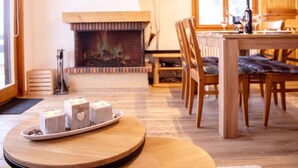 A cozy living room with a fireplace, wooden furniture, and a television mounted on the wall.