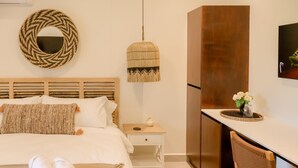 A neatly arranged hotel room with a bed, bedside table, and a small desk area. - Palma Verde Arenal (La Fortuna)