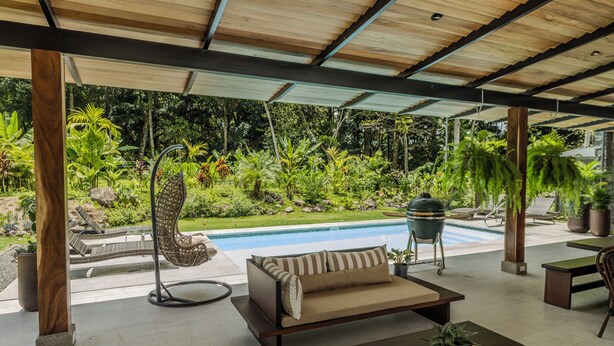 A covered outdoor area with a pool, a sofa, and various plants. - Palma Verde Arenal (La Fortuna)