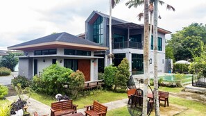 A modern two-story house with a large glass window, a swimming pool, and outdoor seating. - ProudChan Boutique Resort (Chanthaburi)