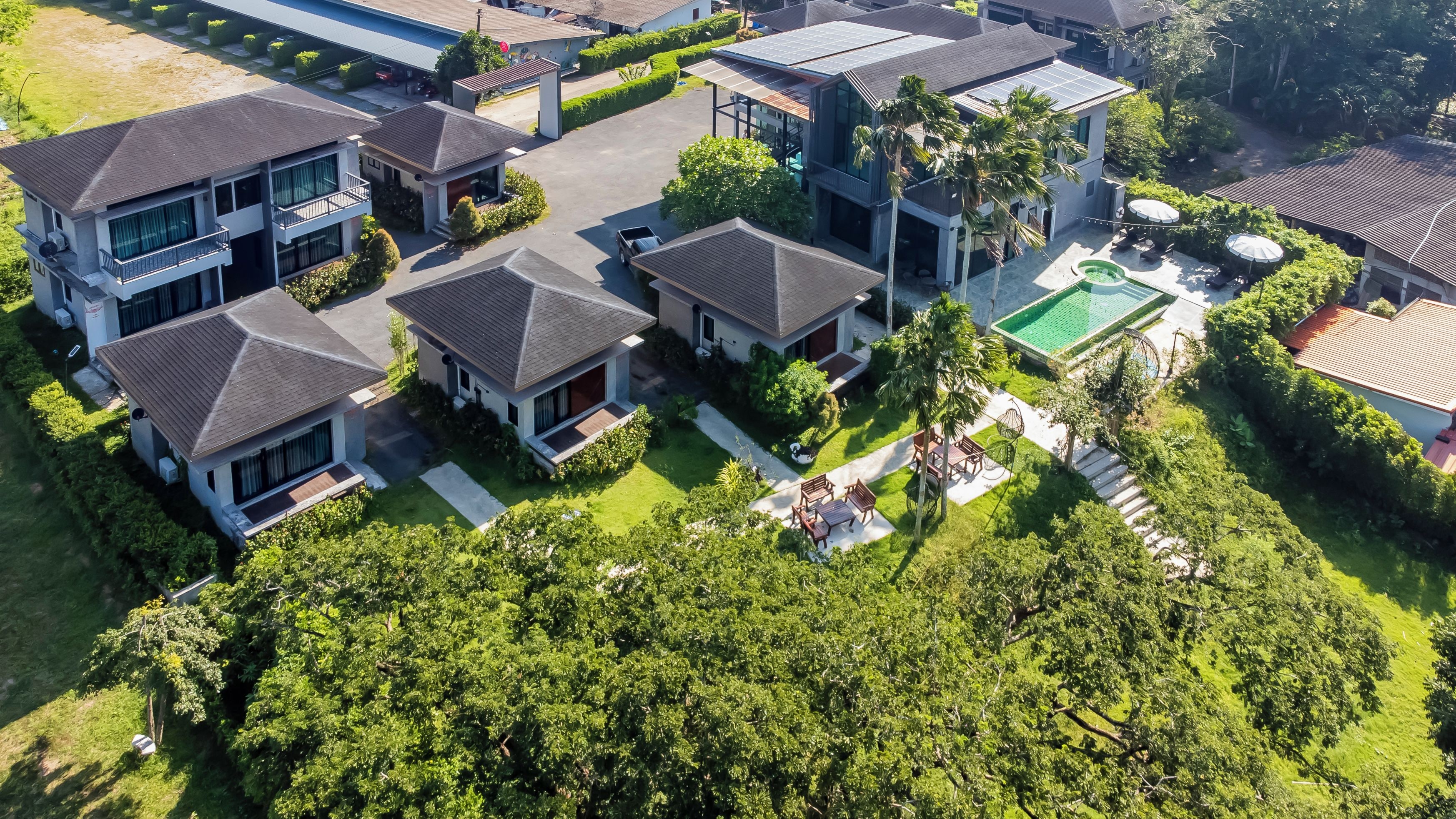A residential complex with multiple houses, a swimming pool, and well-maintained gardens.