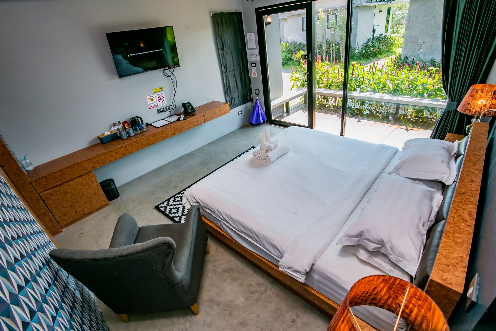 Habitación de hotel con cama, escritorio con televisor de pantalla plana, una silla y vistas al exterior.