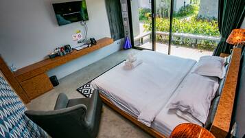 Habitación de hotel con cama, escritorio con televisor de pantalla plana, una silla y vistas al exterior.