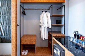 A walk-in closet with a hanging rack, shelves, a wooden bench, and a refrigerator. - ProudChan Boutique Resort (Chanthaburi)