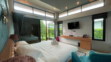 A modern hotel room with a large bed, a desk, a TV, and a balcony with a view.