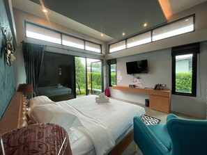 A modern hotel room with a large bed, a desk, a TV, and a balcony with a view. - ProudChan Boutique Resort (Chanthaburi)
