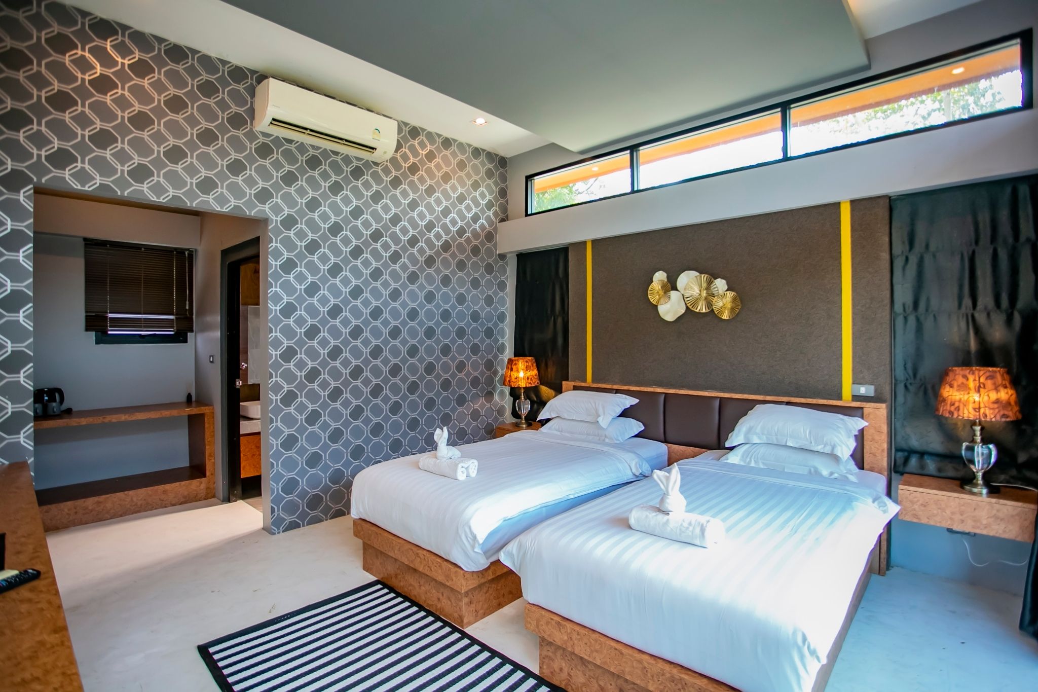 A modern hotel room with two beds, a built-in desk, and a large window.