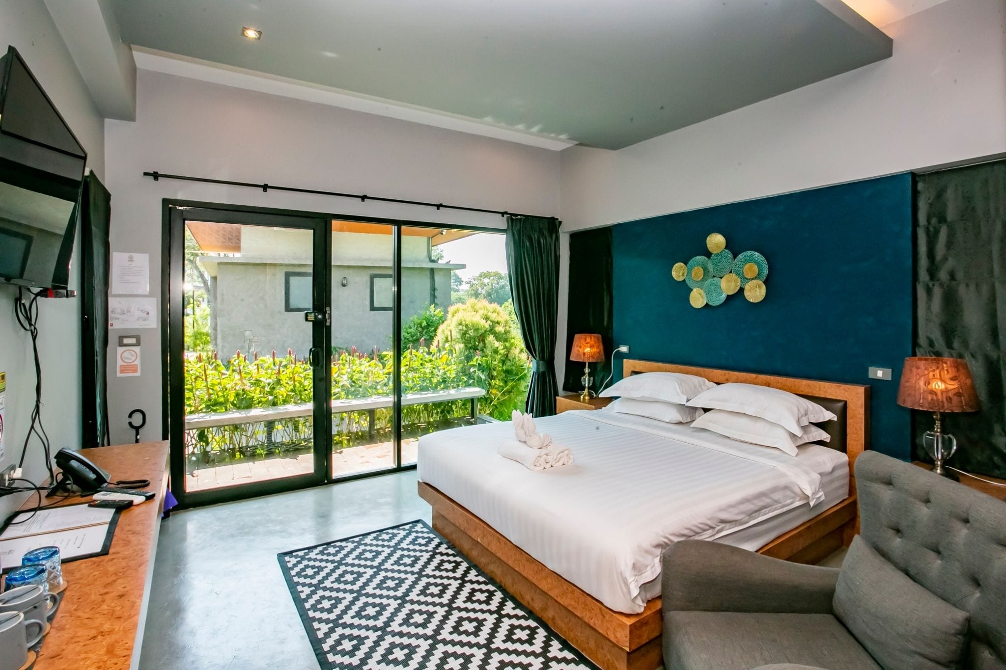 Habitación de hotel con cama, escritorio, silla, televisor y vistas al exterior.