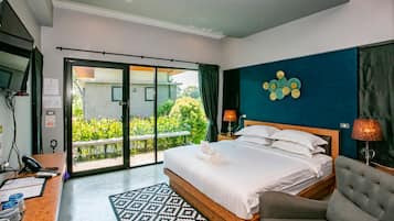 Habitación de hotel con cama, escritorio, silla, televisor y vistas al exterior.