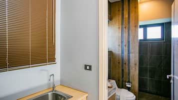 Un baño con tocador de madera, lavamanos y retrete.