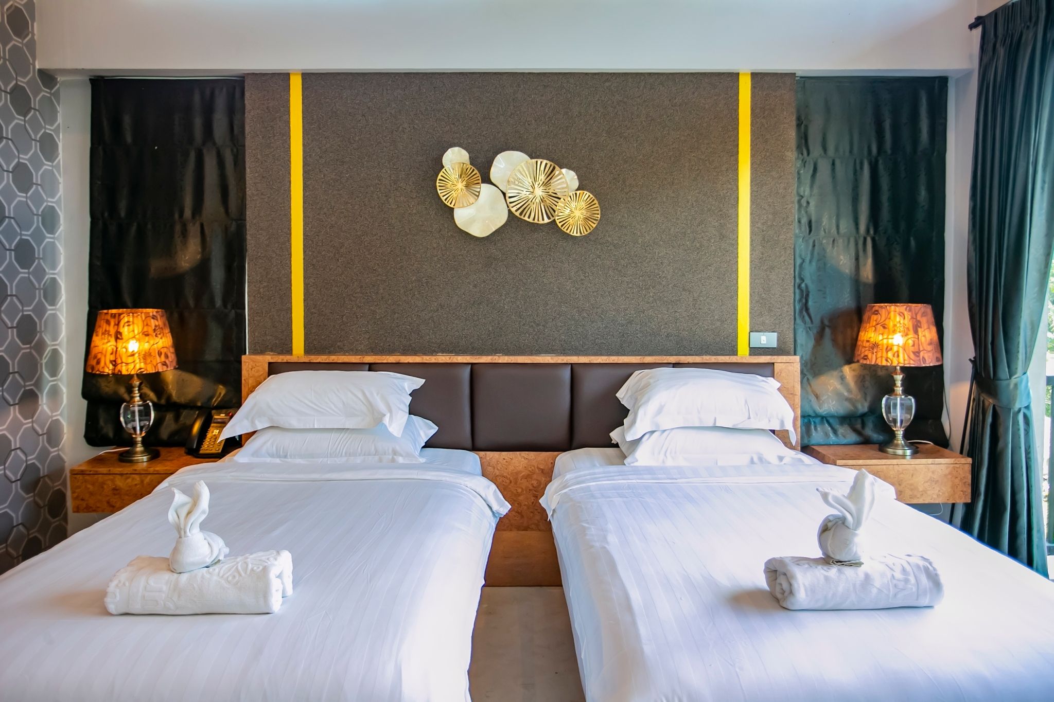 Habitación de hotel con dos camas, un adorno en la pared y lámparas.