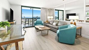 A modern living room with a sofa, armchairs, a coffee table, and a TV. There is a balcony with a view. - SunDestin 1BR Condo With Bunks, Balcony Views and Sleeps 6 - Unit 0202 (Destin)