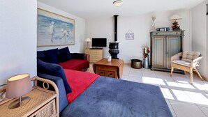 A room with a sofa, a television, a fireplace, a cabinet, and a chair.