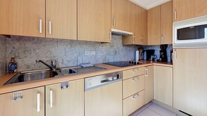 A modern kitchen with wooden cabinets, a stainless steel sink, a Bosch dishwasher, and a microwave.