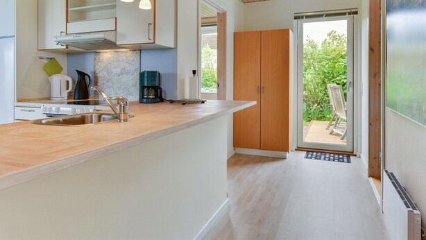 Una cocina moderna con armarios de madera, estufa integrada e iluminación colgante.