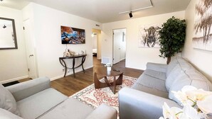 A modern living room with a grey sofa, a coffee table, and a TV mounted on the wall.