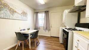 A compact kitchen with a dining table, chairs, a stove, and cabinets.