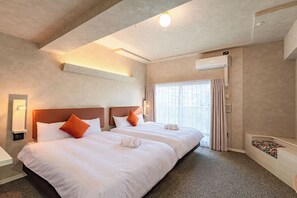 Una habitación de hotel con dos camas, un ventanal con cortinas, un aire acondicionado y piso alfombrado.