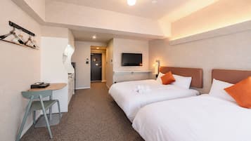A hotel room with two beds, a desk, a chair, a TV, and a bathroom.