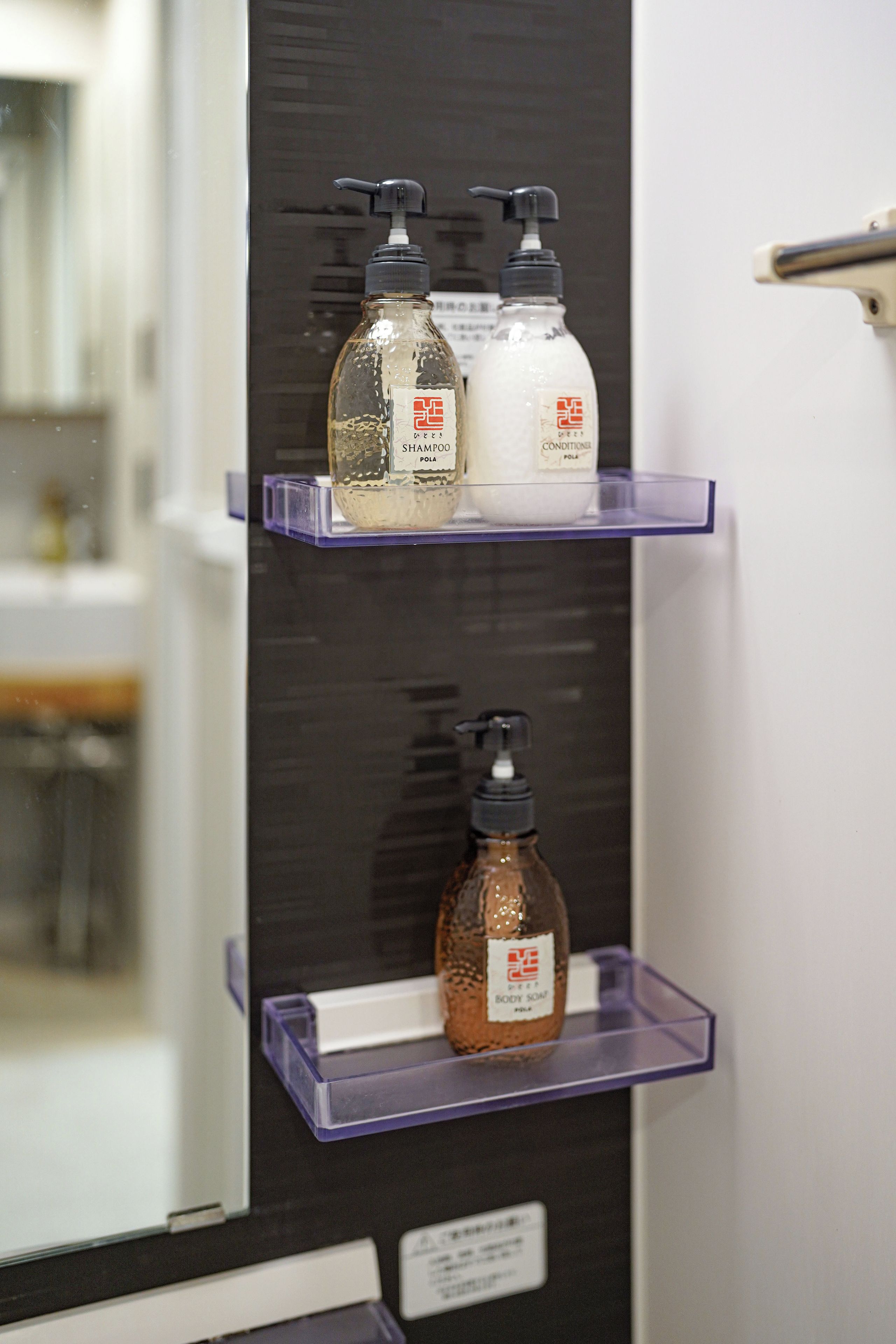 A bathroom shelf with three bottles of toiletries.