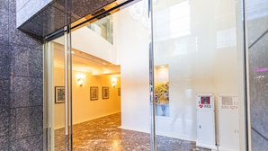 A lobby with marble flooring, glass doors, framed artwork on the walls, and AED emergency signs. - Apartment Hotel 11 Umeda (Osaka)