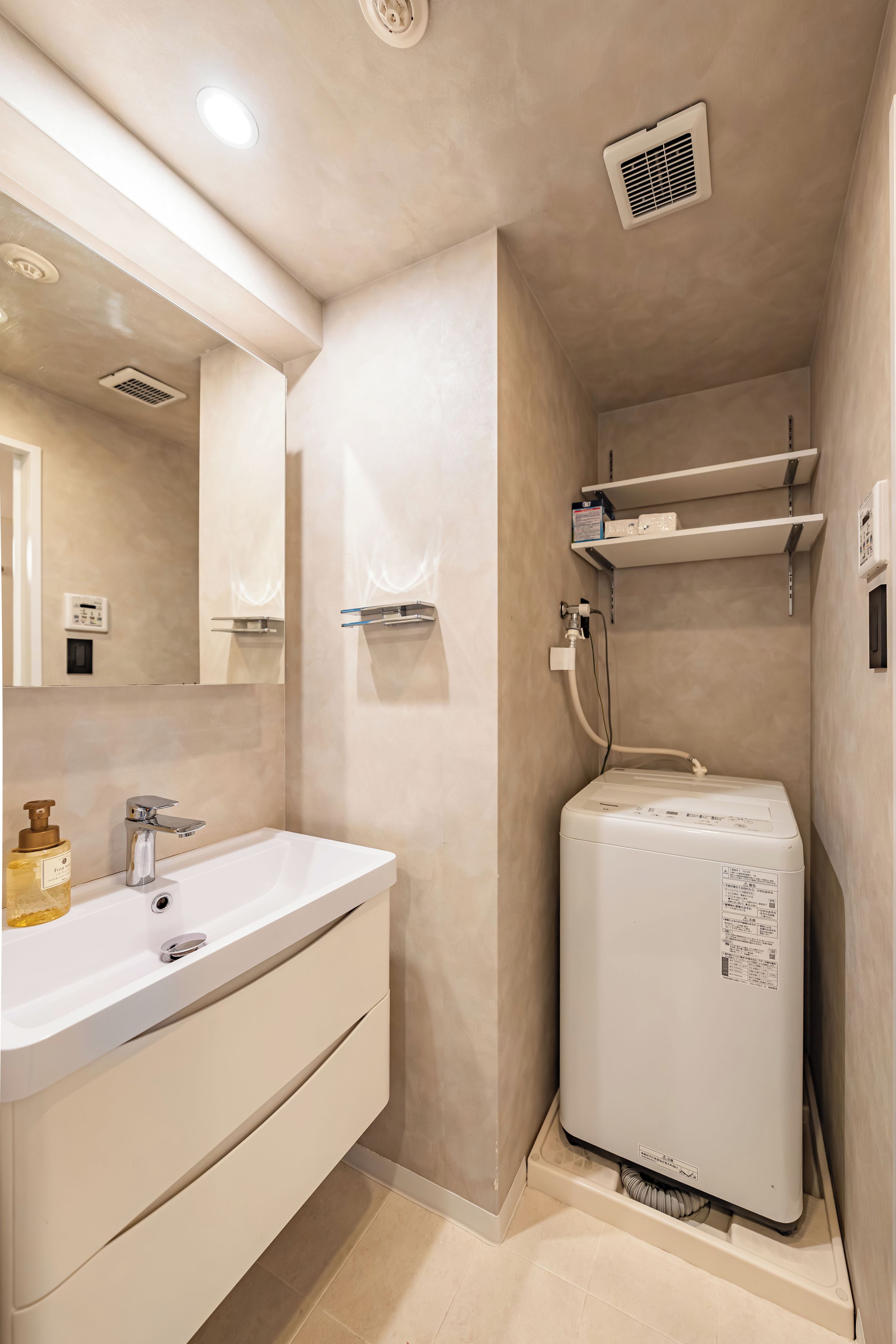 A bathroom with a white sink, mirror, and a white washing machine.