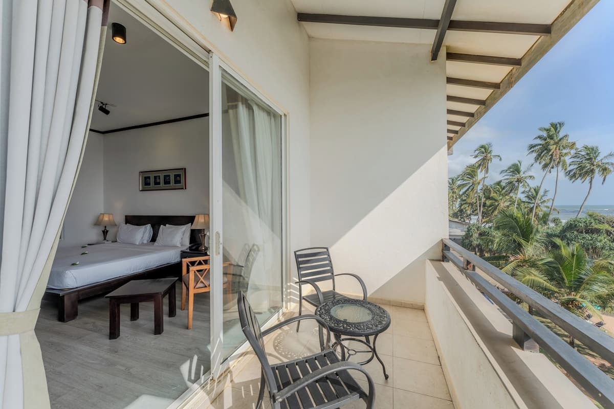 A balcony with a bed, chairs, and a table.