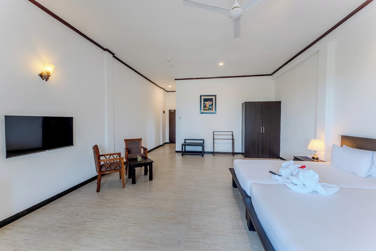 A hotel room with a bed, a desk, a chair, a TV, a wardrobe, and a picture on the wall.
