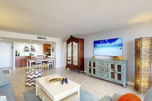 Una sala de estar moderna con comedor, televisor grande y un mueble decorativo.
